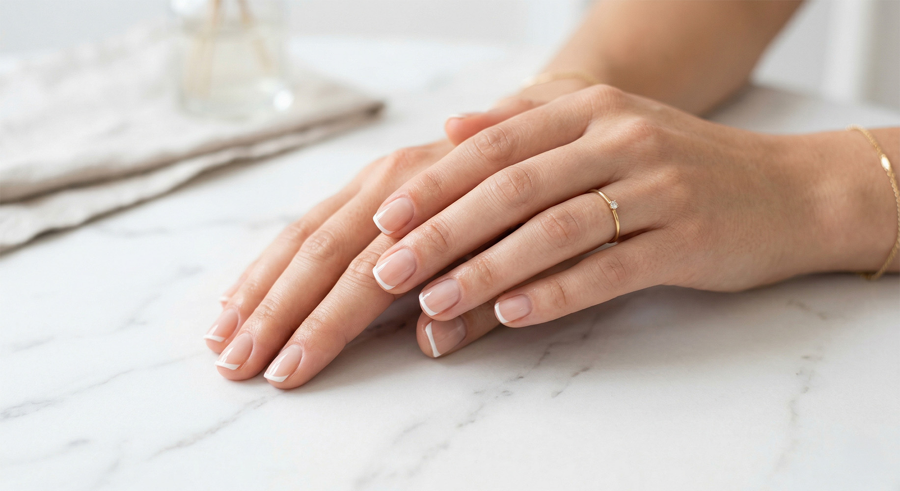 Elegancki micro french manicure na krótkich paznokciach na białym marmurze